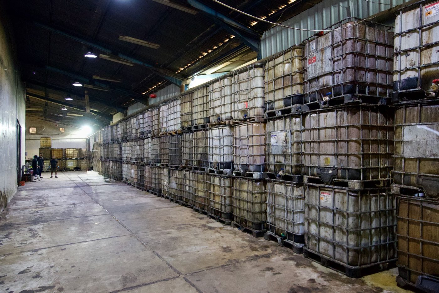 Entrepôt de cuves IBC d'huiles alimentaires usagées, empilées sur plusieurs rangées